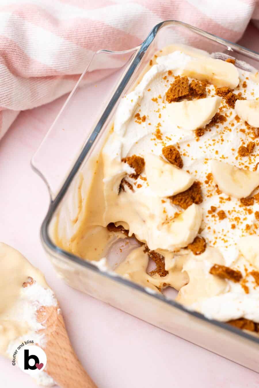 Thick and creamy inside of Biscoff banana pudding in a casserole dish revealing layers of pudding, cookies, bananas, and whipped cream.