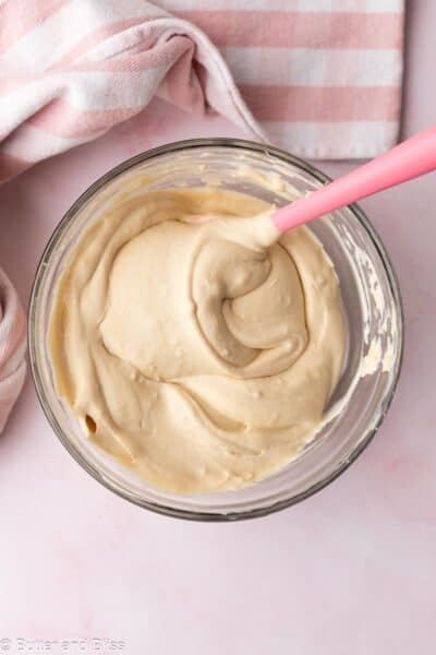 Thick and creamy whipped cream lightened Biscoff pudding in a mixing bowl with a pink spatula.