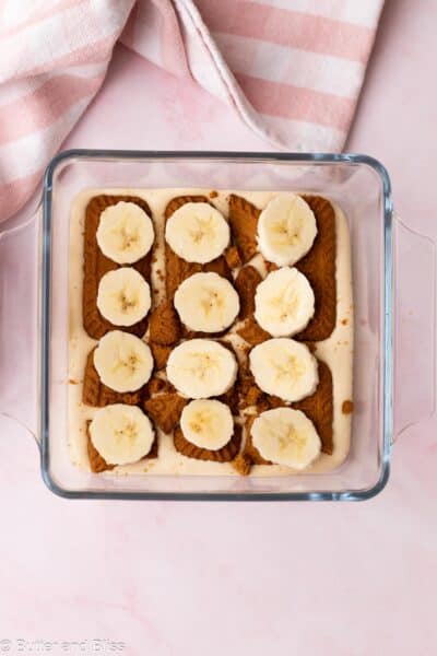 Banana slices placed on top of Biscoff cookies in a small casserole dish.