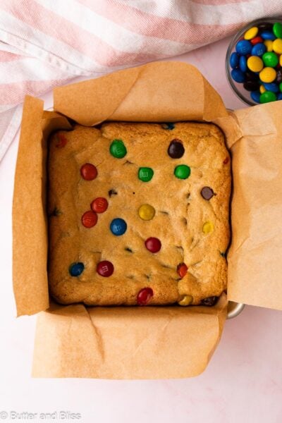 Fresh baked M&M cookie bars cooling in a square pan.