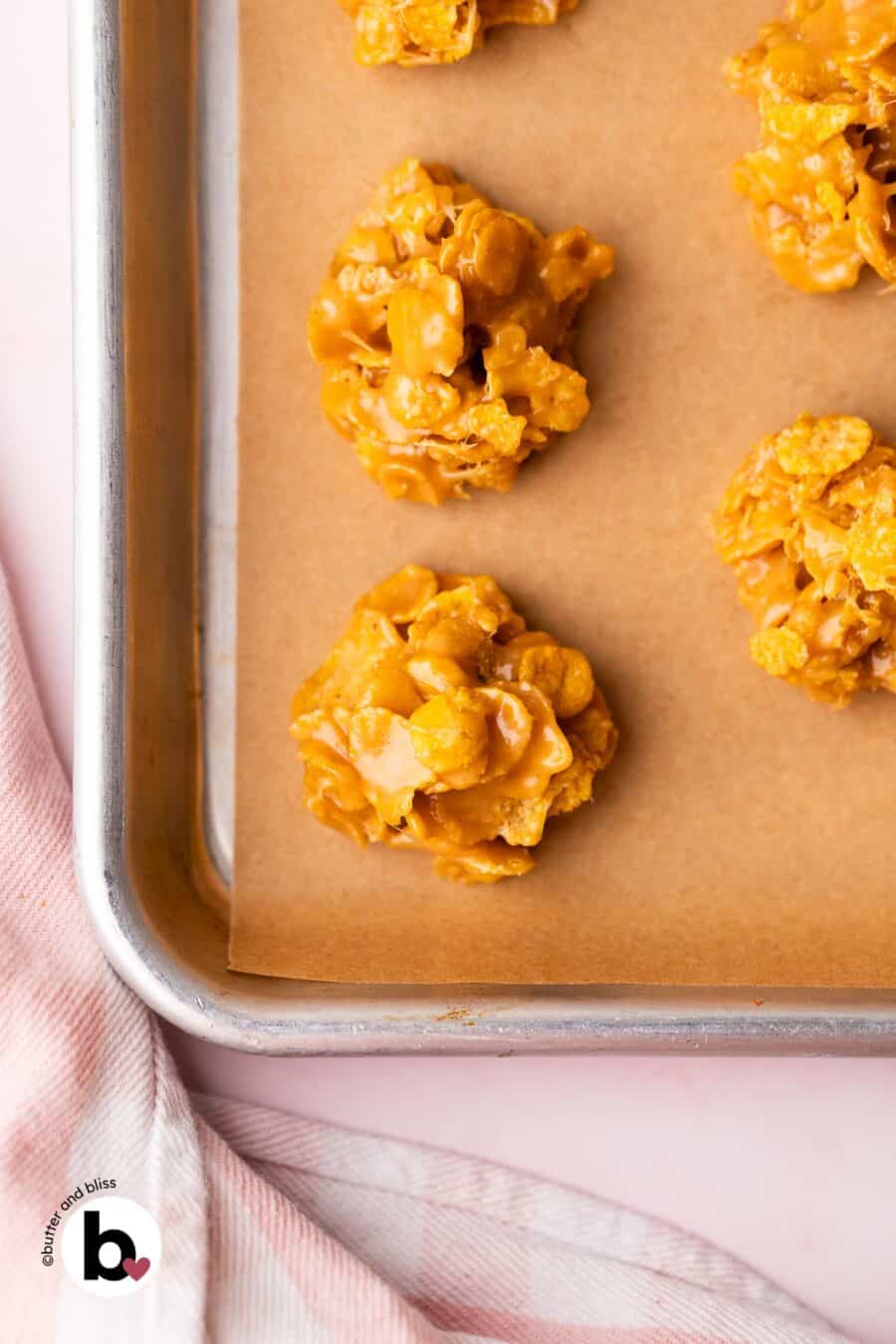 Peanut butter cornflake no-bake cookies on a parchment lined baking sheet.