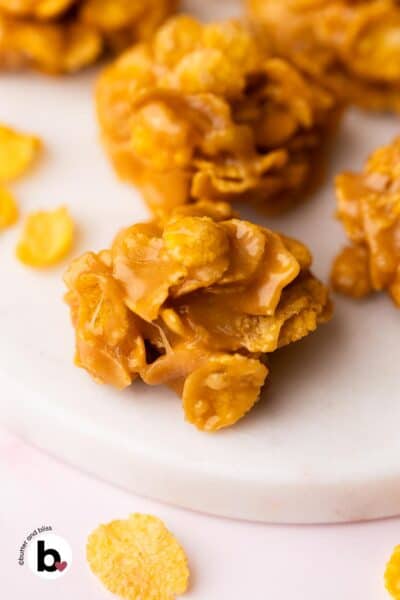 Shiny peanut butter cornflake no-bake cooie on a white marble plate.