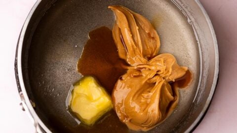 Peanut butter and butter added to a small saucepan of melted sugar.