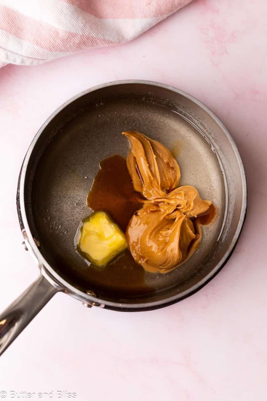Peanut butter and butter added to a small saucepan of melted sugar.