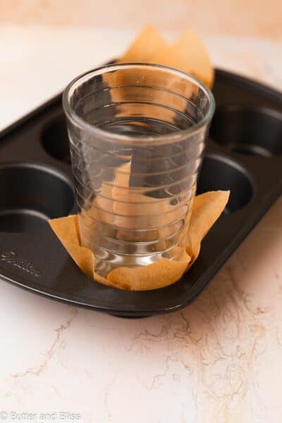 Glass pressing a DIY tulip liner into a muffin pan.