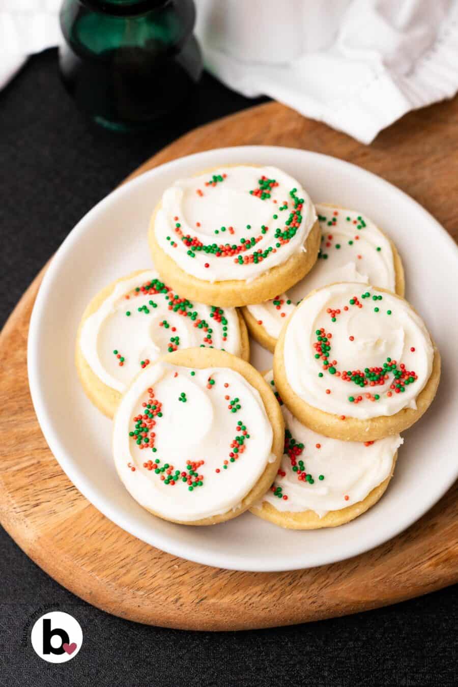 A plate of frosted butter cookies decorated with red and green sprinkles.