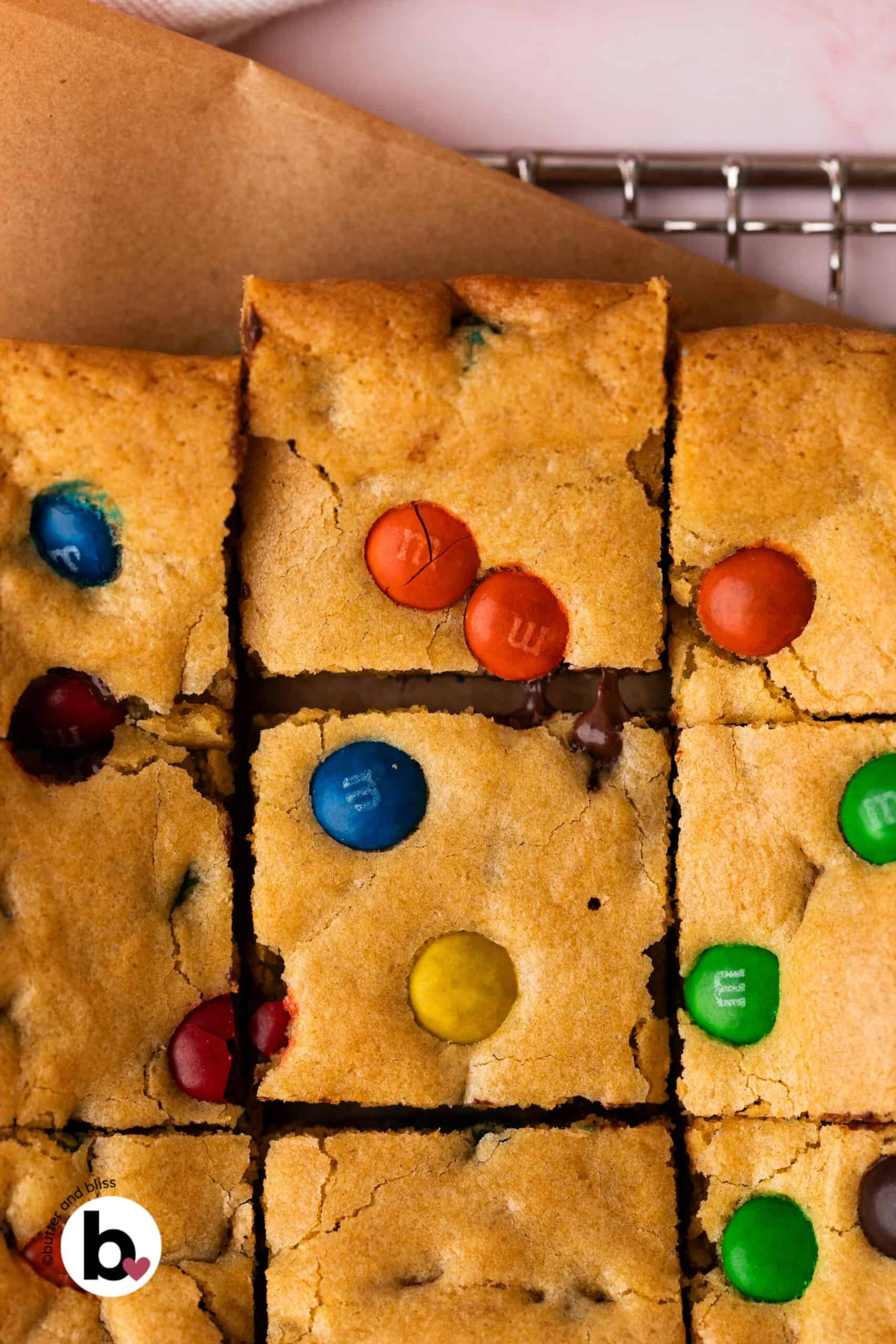 M&M cookie bars cut into square with one pulled away showing melty chocolate.