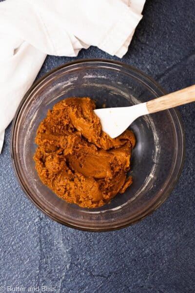 Thick and sticky molasses cookie dough in a mixing bowl with a spatula.