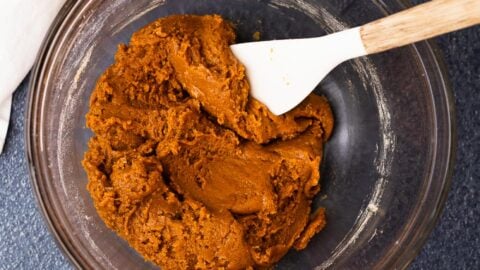 Thick and sticky molasses cookie dough in a mixing bowl with a spatula.