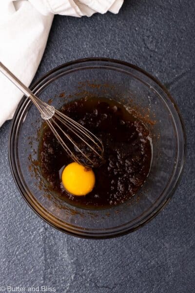Egg yolk added to a mixing bowl of melted butter and sugar.