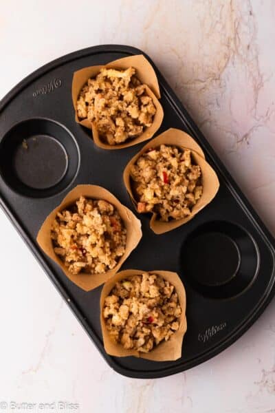 Apple pumpkin muffins covered generously in streusel in a muffin pan.