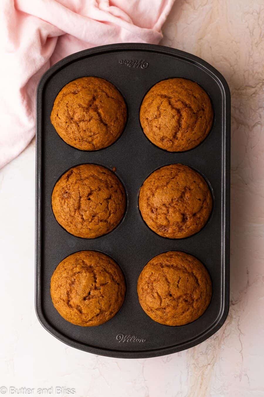 Fresh baked pumpkin cupcakes in a 6-well cupcake pan.