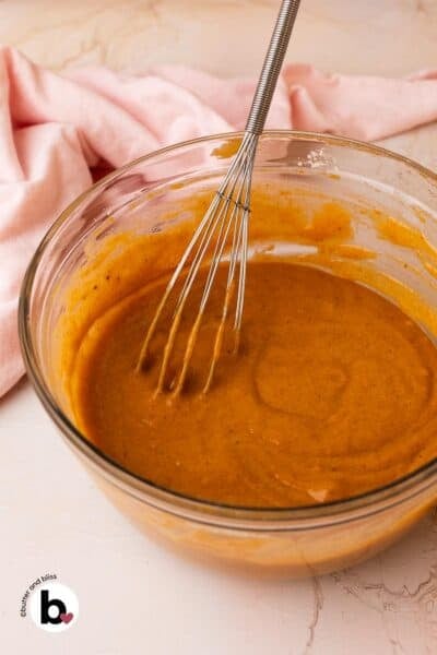 Pumpkin cupcake batter in a mixing bowl with a whisk.
