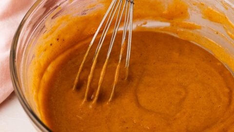 Pumpkin cupcake batter in a mixing bowl with a whisk.