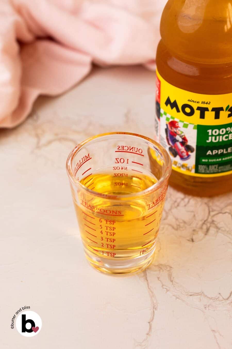 Small measuring cup of apple juice.