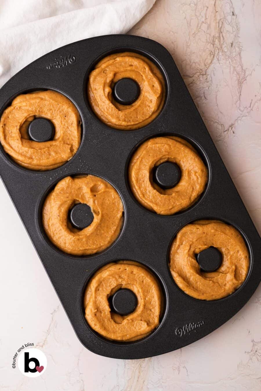Pumpkin batter in a donut pan, ready to be baked.