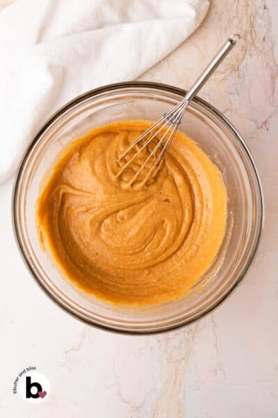 Pumpkin batter in a mixing bowl with a whisk.