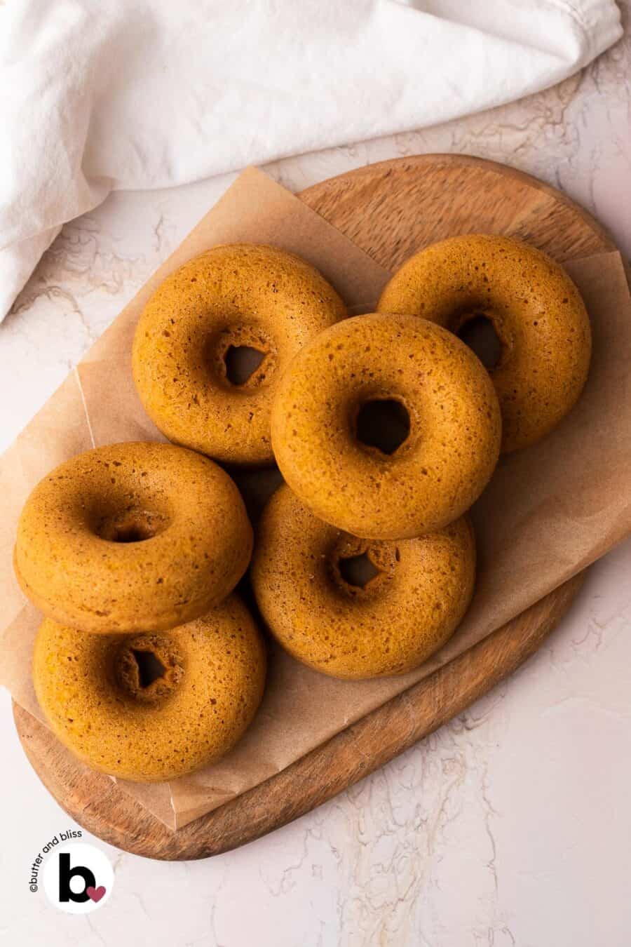 Fresh baked small batch pumpkin donuts on a wood platter.