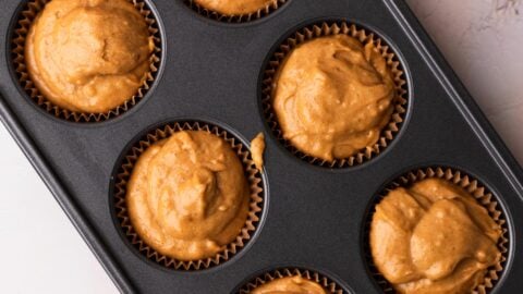 Pumpkin muffin batter liners in a muffin pan.