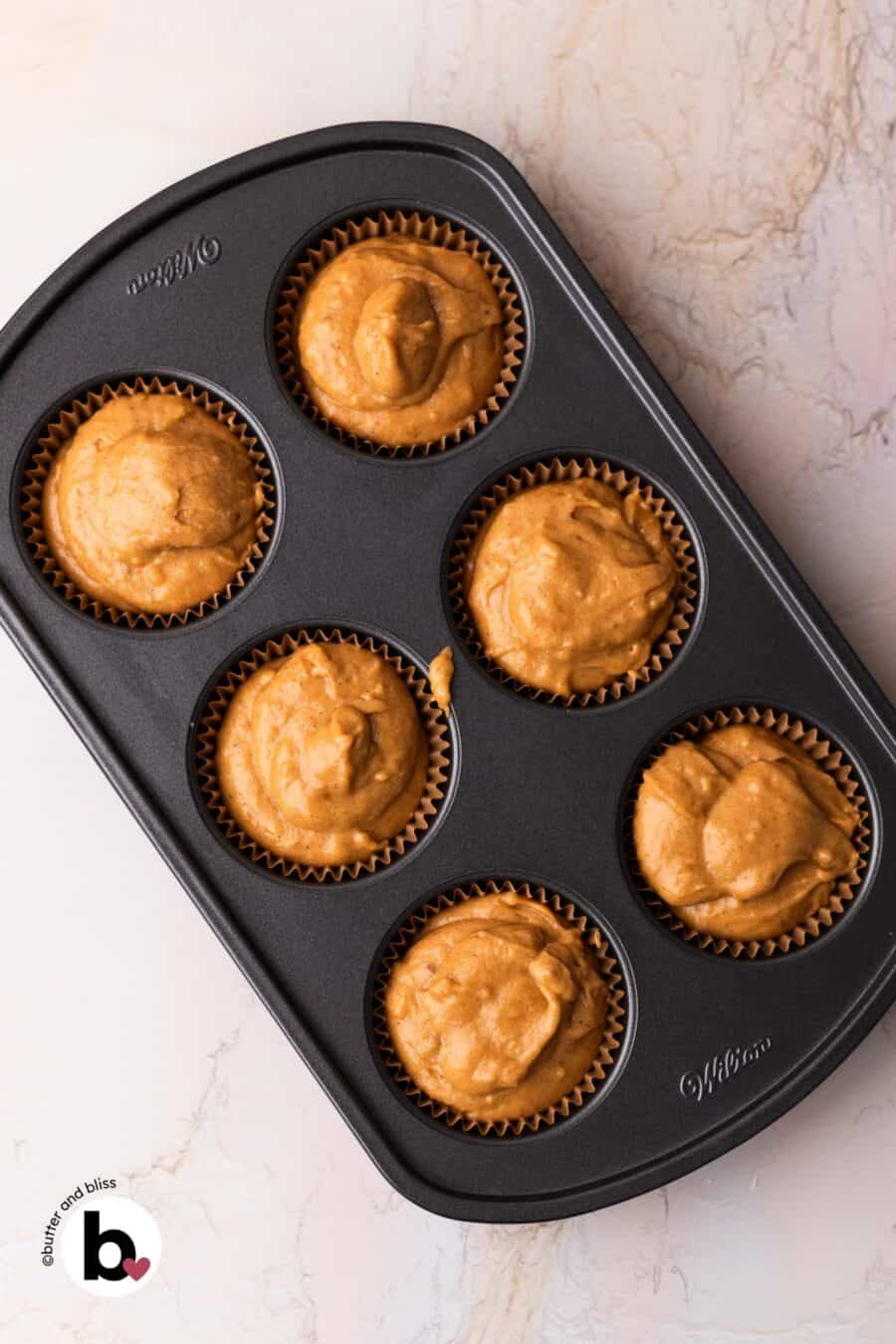 Pumpkin muffin batter liners in a muffin pan.