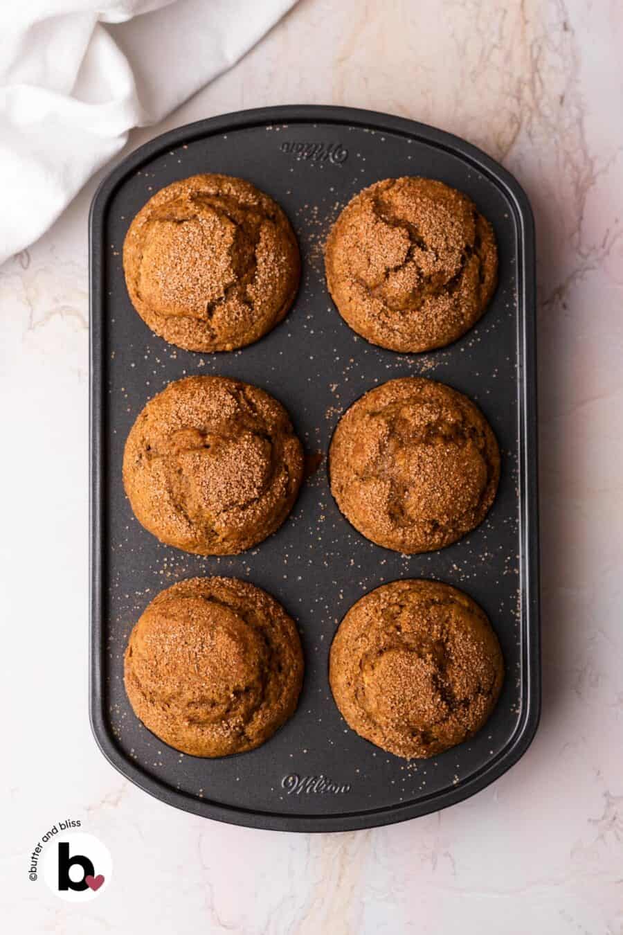 Fresh baked pumpkin muffins with cinnamon sugar sprinkle in a muffin pan.