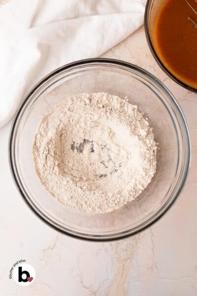 A well made in the center of dry muffin ingredients in a mixing bowl.