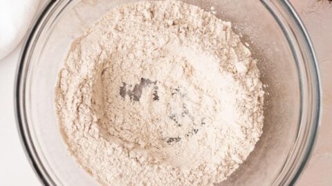A well made in the center of dry muffin ingredients in a mixing bowl.