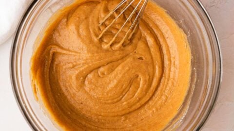 Smooth pumpkin muffin batter in a mixing bowl with a whisk.