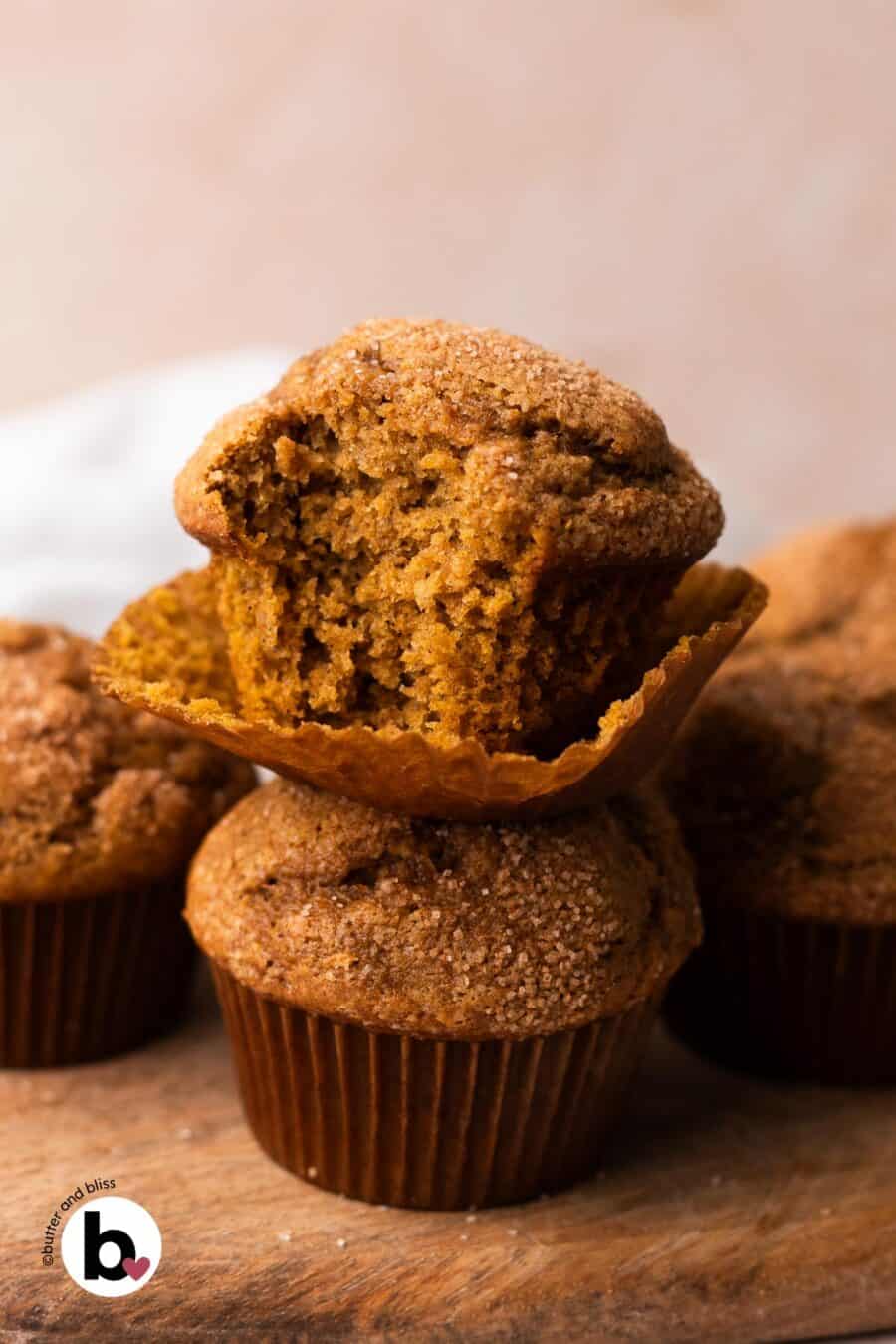 A stack of two pumpkin muffins with a bite taken out of the top one to reveal the moist center.