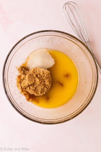 Melted butter and sugars in a mixing bowl with a whisk.