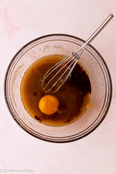 Egg add to a mixing bowl of melted butter and sugars.
