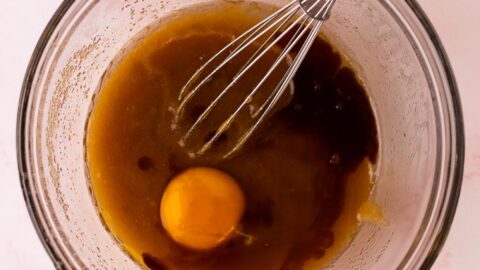 Egg add to a mixing bowl of melted butter and sugars.