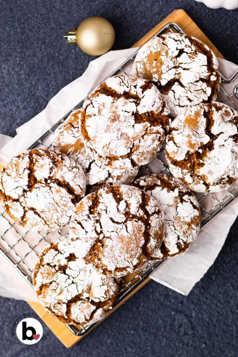 Fresh baked molasses crinkle cookies piled on a wood cutting board.