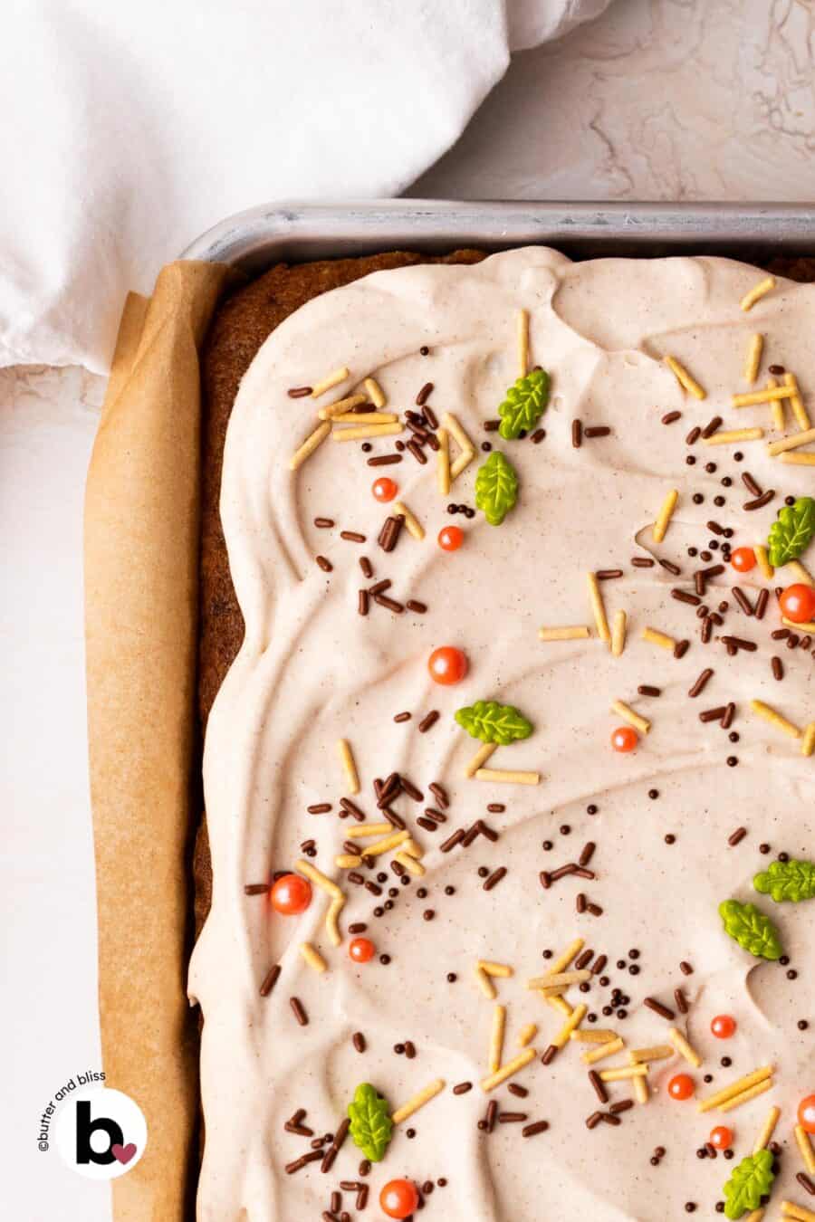 Corner piece of a cream cheese frosted pumpkin bar with seasonal sprinkles.
