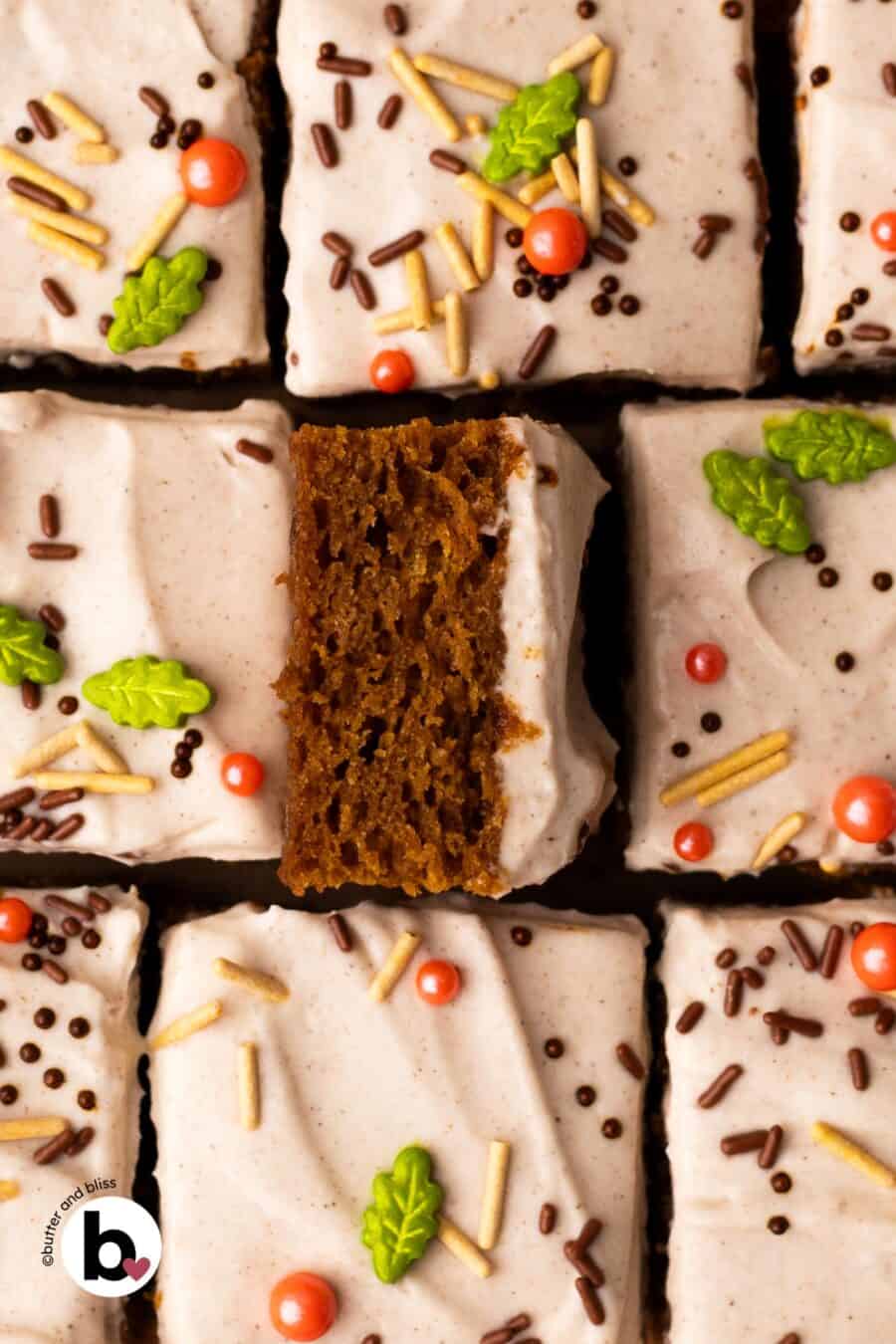 Cream cheese frosted pumpkin bar square flipped up to show moist center.