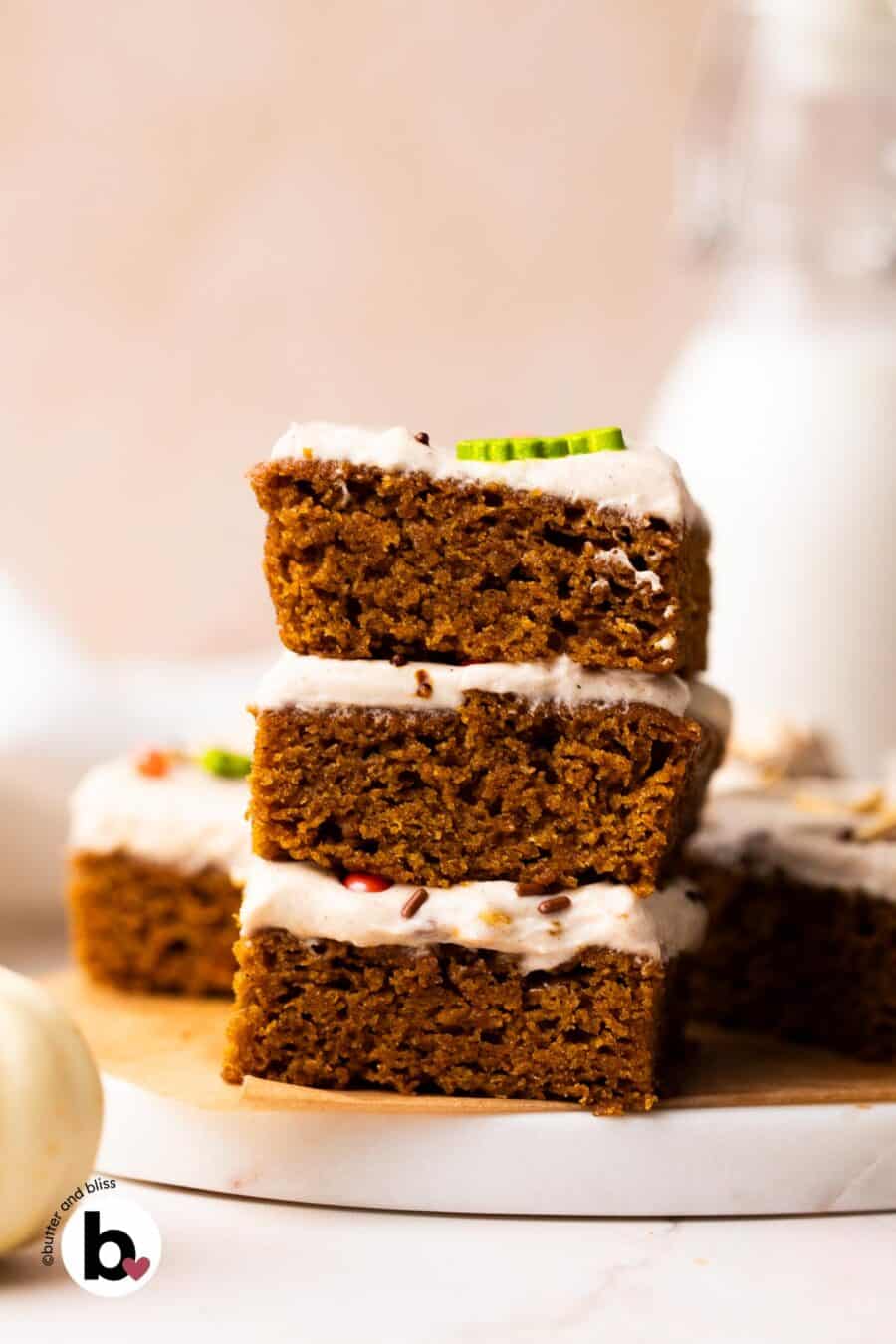 A stack of three pumpkin bar squares on a marble plate.