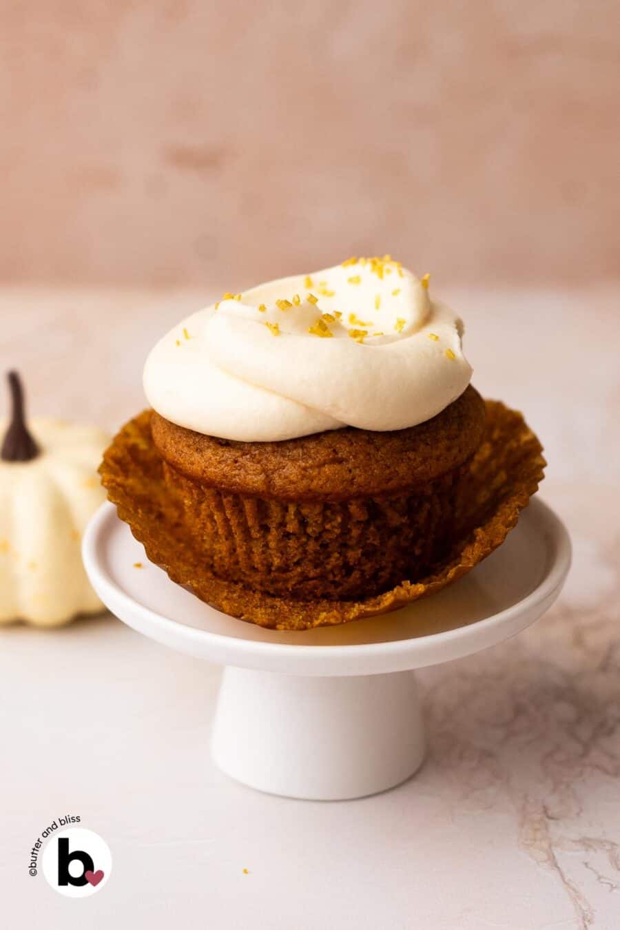 Single pumpkin cupcake with the liner peeled back on a mini cupcake stand.