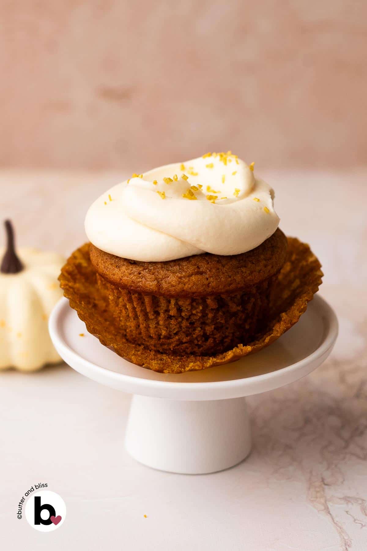 Single pumpkin cupcake with the liner peeled back on a mini cupcake stand.