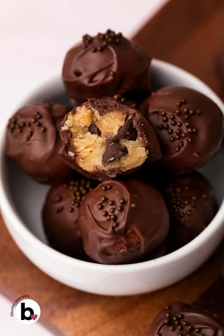 Bite taken out of a chocolate covered cookie dough bite revealing creamy edible cookie dough.