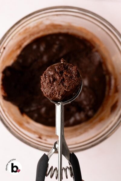 Fudgy chocolate crinkle cookie dough in a cookie scoop.