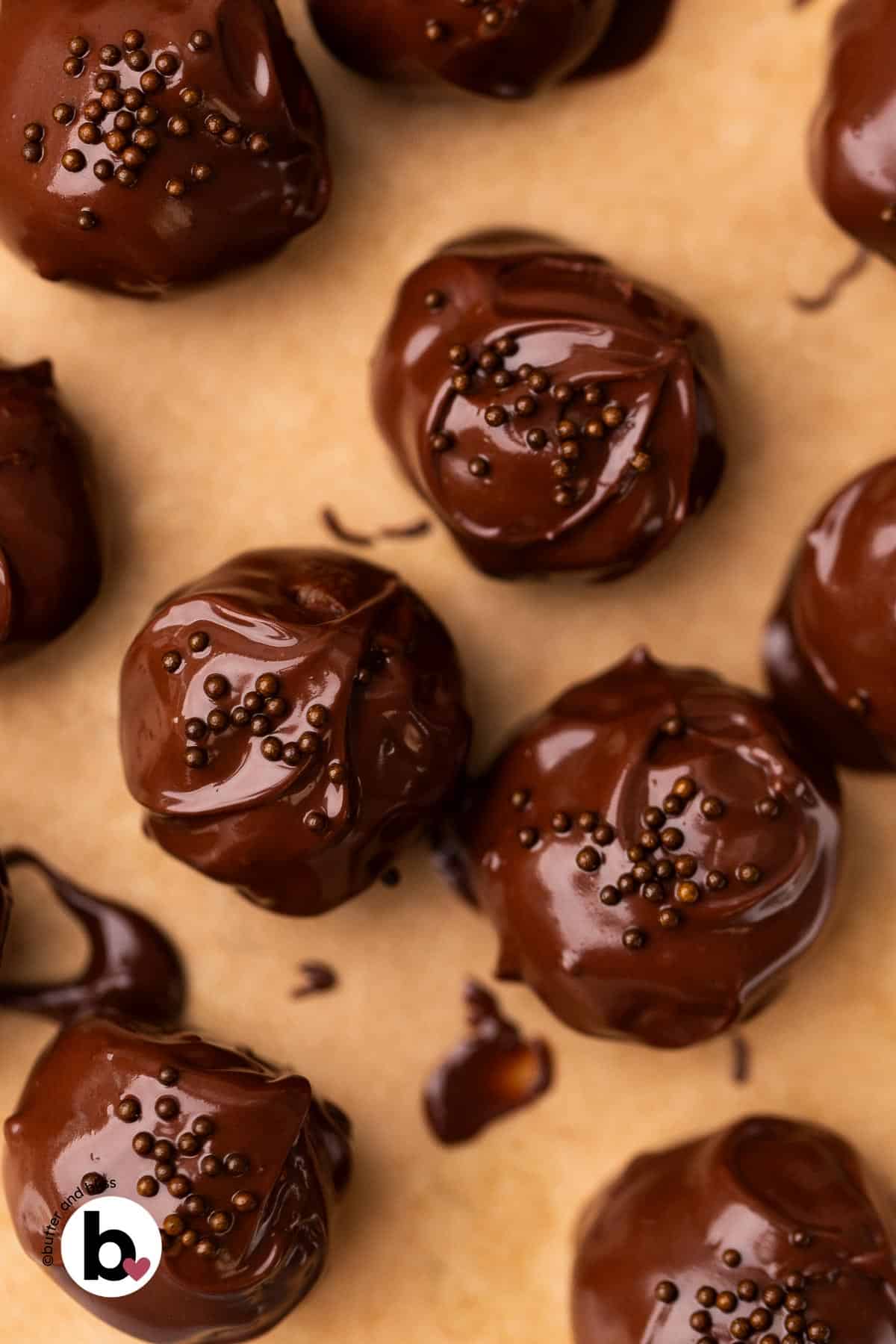 Chocolate covered cookie dough bites with chocolate sprinkles on a baking sheet.