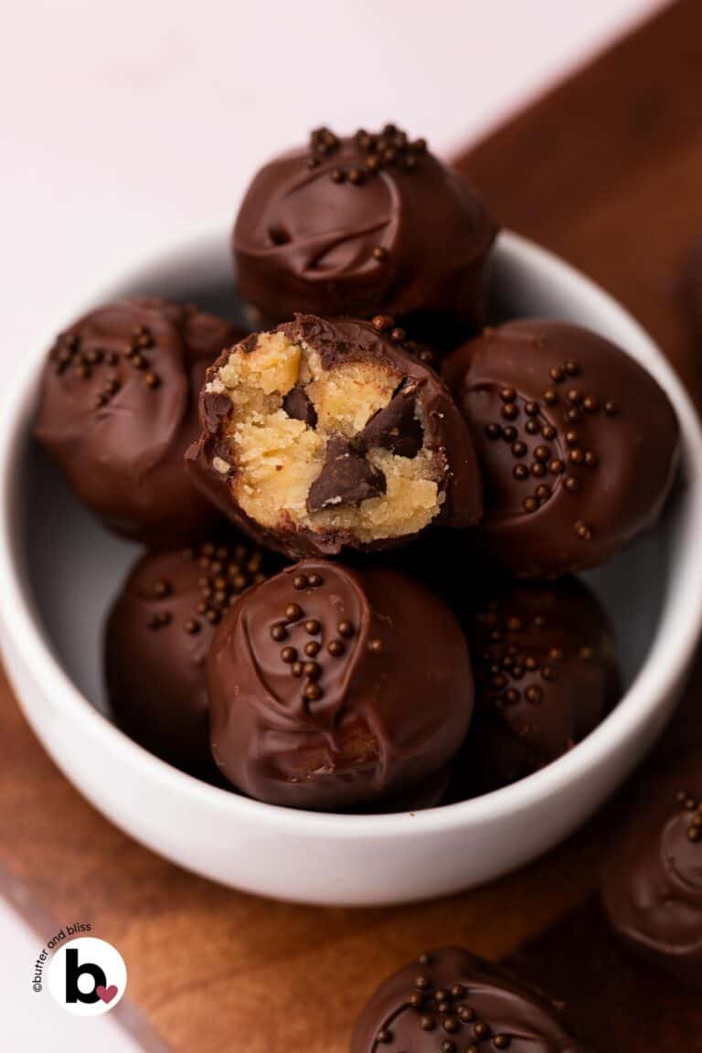 Bite taken out of a chocolate covered cookie dough bite revealing creamy edible cookie dough.