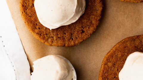 Light cream cheese frosting scooped onto a pumpkin whoopie pie.