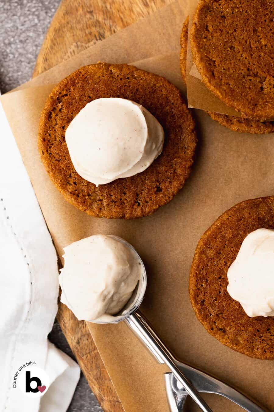 Light cream cheese frosting scooped onto a pumpkin whoopie pie.