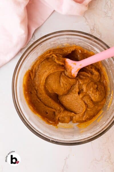 Pumpkin whoopie pie batter in a mixing bowl with a pink spatula.