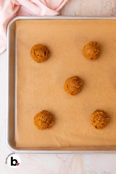 Pumpkin whoopie pie batter scoops on a baking sheet.