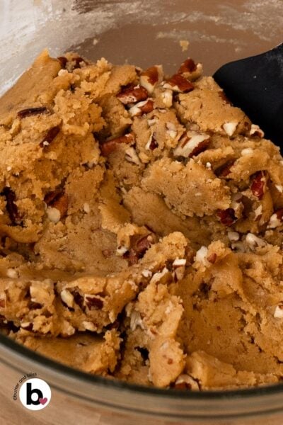 Maple brown sugar cookie dough studded with pecans in a mixing bowl.