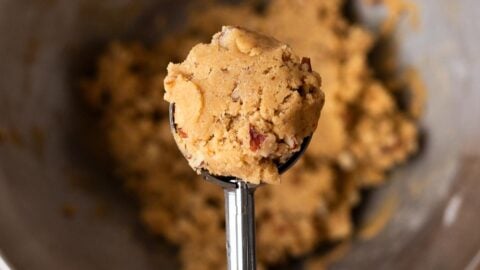 Hand holding a cookie scoop full of maple brown sugar cookie dough.