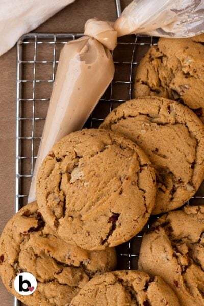 Small batch maple brown sugar cookies stacked on a wire rack next to a piping bag of glaze.