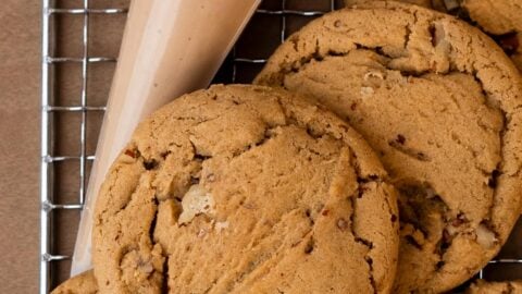 Small batch maple brown sugar cookies stacked on a wire rack next to a piping bag of glaze.